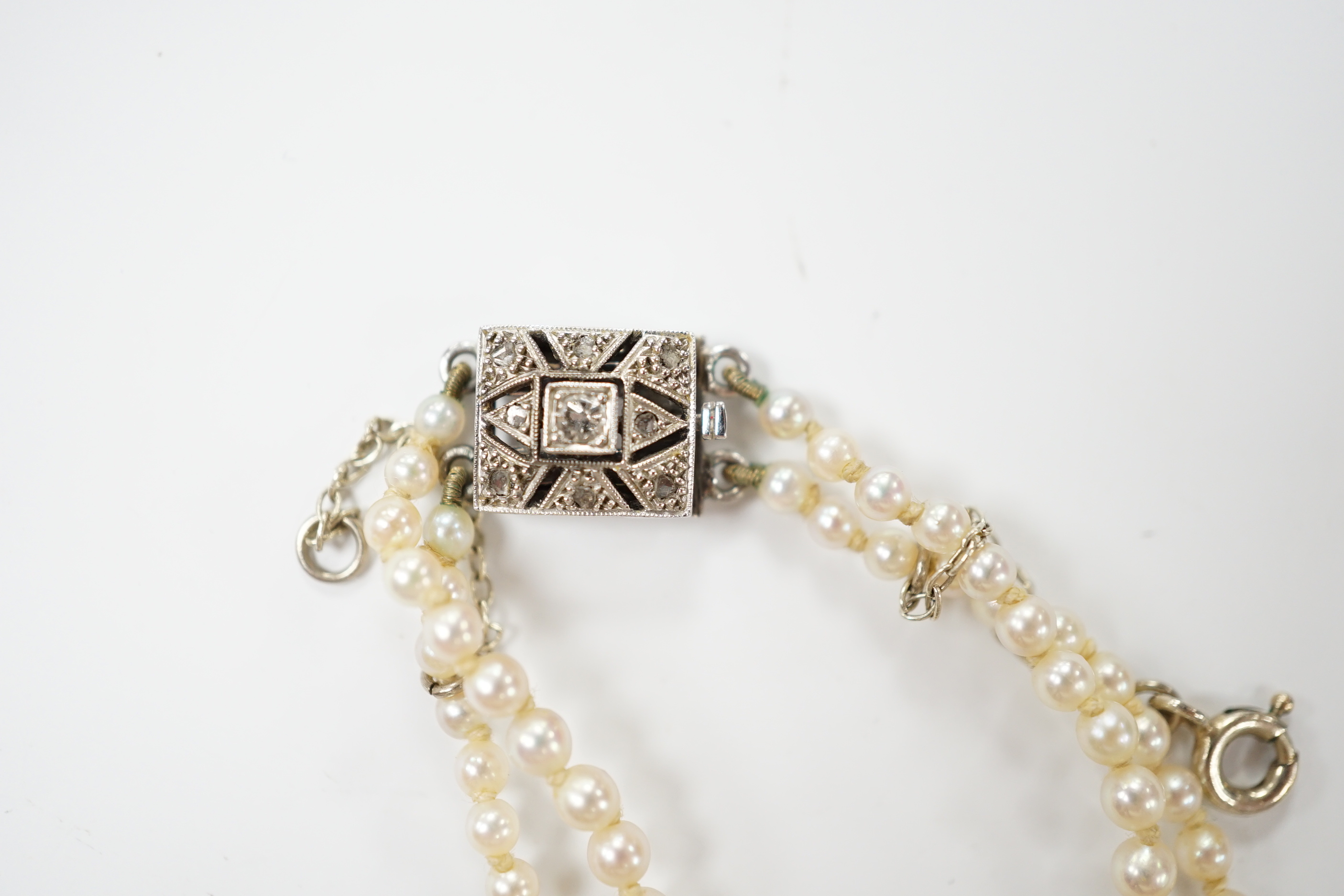 A 1940's French double strand graduated cultured pearl necklace, with diamond set white metal clasp (18ct poincon mark), 46cm.